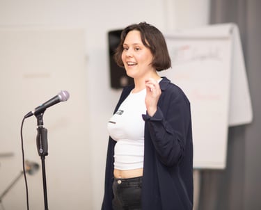 Woman speaking confidently into a microphone while explaining a topic to the group