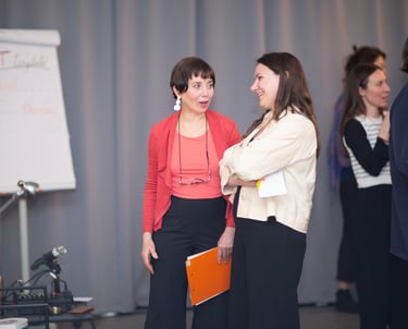 Two women. One public speaking coach, talking with female participant at public speaking workshop. 