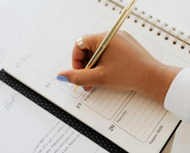 Mano con bolígrafo dorado escribiendo en una agenda especial