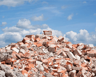 Enorme monte de entulho com restos de tijolos e concreto sob o céu, indicando necessidade de locação de caçamba para remoção