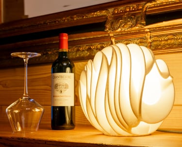 Elegant modern wave lamp glowing next to a bottle of Chanteclerc red wine and an upside-down glass.