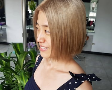 Woman with a stylish ash blonde bob haircut and straight hair at a professional salon.