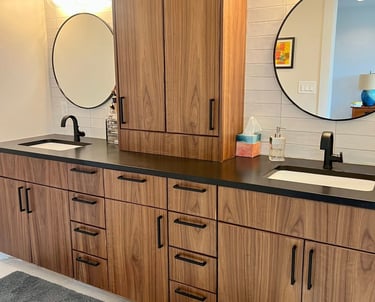 Modern bathroom double vanity with walnut wood cabinets, black hardware, and round mirrors.