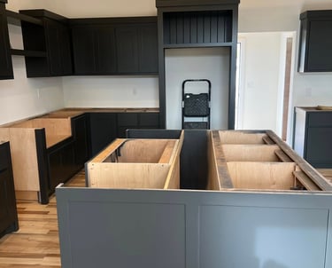 Modern kitchen remodel featuring dark gray cabinets and a large island with hardwood floors.