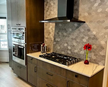 Modern kitchen featuring brown wood cabinets, a black vent hood, and a grey hexagon tile backsplash.