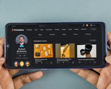 A person holding a smartphone displaying the Printables website with 3D printing models.