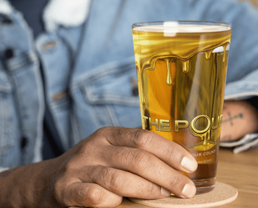 The Pour Shop branded pint glass shown in packaging box with materials demonstrating hospitality merchandise presentation