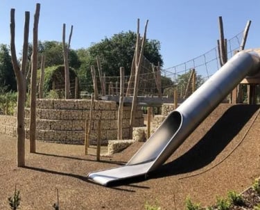 Playground moderno com escorregas, cordas para escalar, balanços e áreas separadas por faixa etária.