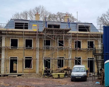 Town houses under construction with scaffolding, a slate tiled roof.