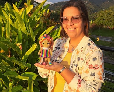 Una persona sonriendo sosteniendo un amigurumi con un vestido multicolor