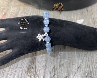 Aquamarine beaded bracelet with a silver flower charm on a black velvet display hand.