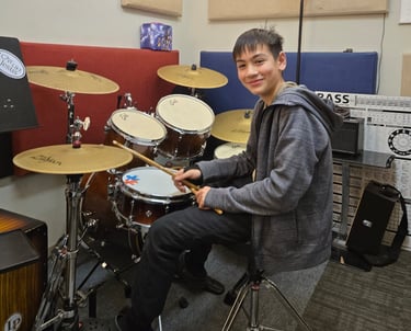 Teenager learning to play the drum set.
