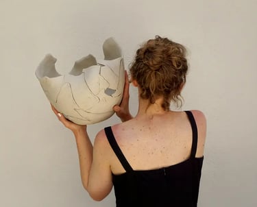 La artista ceramista Claire Lippmann sosteniendo una de sus esculturas a espaldas de la cámara.