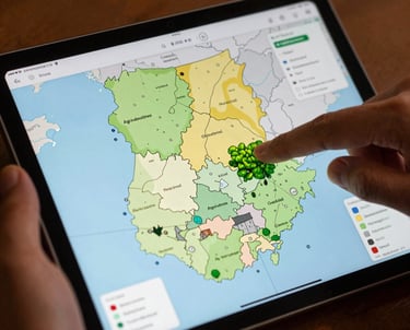 A photograph showing a digital tablet with a map of Ghana's agricultural regions. A hand is pointing to a specific cluster. Professional setting with warm lighting.