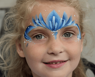 Alt-tekst: Glimmachend meisje met een blauw-wit geschminkte ijsprinsessenkroon.