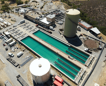 Aerial view; large water treatment or industrial processing facility with treatment ponds, storage tanks, and infrastructure