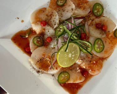 Aperitivo de carpaccio de vieira fresca con lima, rodajas de jalapeño y salsa de chile, servido.