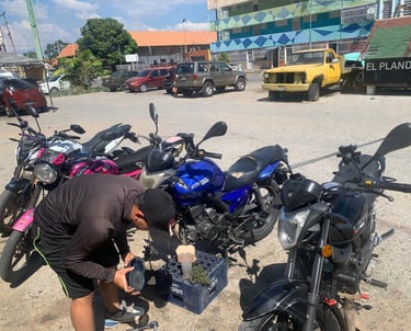 Un mecánico realiza mantenimiento a varias motocicletas Empire Keeway estacionadas en un lote