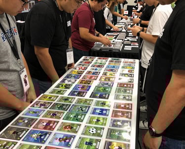 Photo of a bustling indoor hall filled with tables of soccer cards and collectors browsing.