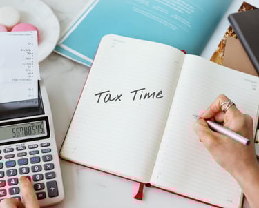 a person writing tax tax calculations on a notebook