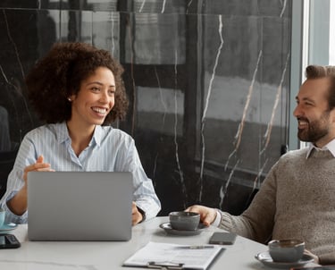 a man and woman sitting at a table with a laptop