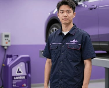 Professional auto mechanic in a navy uniform standing by a purple car on a lift for an oil change.