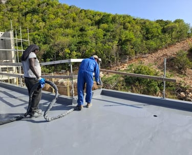 Construction workers applying a grey waterproof coating to a flat roof at The Hills Residence