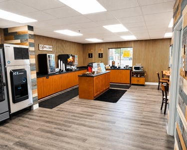 Modern hotel breakfast area and coffee bar with wood paneling, ice machine, and snack station.