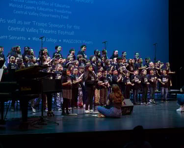 A diverse youth choir performing on a stage during the Central Valley Theatre Festival.