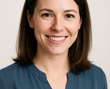 A professional headshot of a female professional with a warm smile, wearing a slate blue blouse. High-key lighting, off white background, modern and clean style. North American / International.
