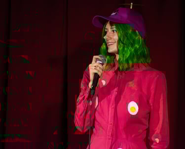 Moira Adomaite performing in a stand up show dressed like pink soup