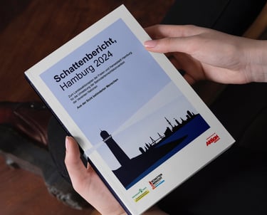 Mann hält gedruckte Broschüre des Schattenbericht Hamburg und schaut aufs Deckblatt