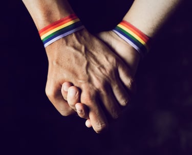 Two men holding hands with pride bands