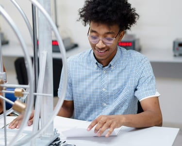 a researcher in a blue shirt is sitting at a table, writing a paper