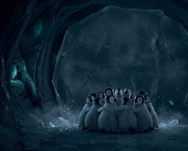 A group of fluffy baby emperor penguin chicks huddle together for warmth inside a dark ice cave.