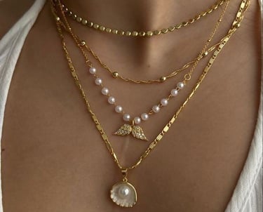 a woman wearing a white top and gold necklaces