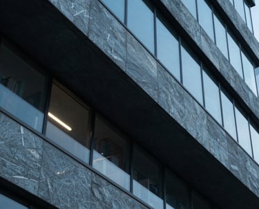 A high-contrast photograph of an architectural detail on a modern research library, featuring sharp angles and slate blue glass.