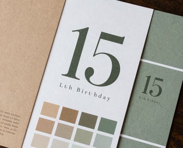 A beautiful arrangement of brand identity elements for a 15th birthday party, including typography sheets and color swatches in tan and sage green.