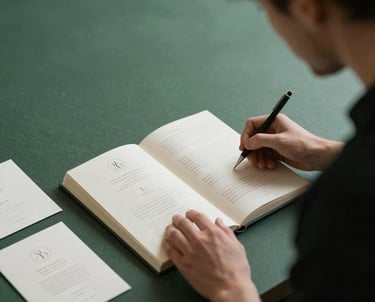 Two professionals in a refined studio discussing a brand manual layout, focusing on elegant wedding stationery, forest green and cream environment.