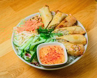 a bowl of vermicelli salad with spring rolls.