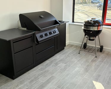 Modern outdoor kitchen featuring a black built-in gas grill and a charcoal kettle grill.