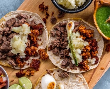 Auténticos tacos callejeros mexicanos con carne de res y chorizo ​​en una tabla de madera con salsa 