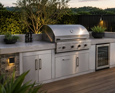 Modern outdoor kitchen with a stainless steel gas grill, concrete countertops, and built-in fridge.