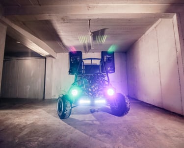 Custom off-road dune DJ buggy with LED lights and a loud audio speaker system in a concrete garage.