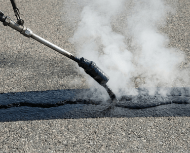 Shows filling a crack with hot tar