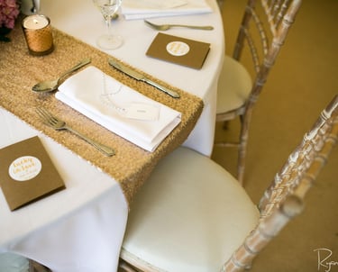 Elegant wedding table setting with gold sequin runner, white linen napkins, and silver cutlery.