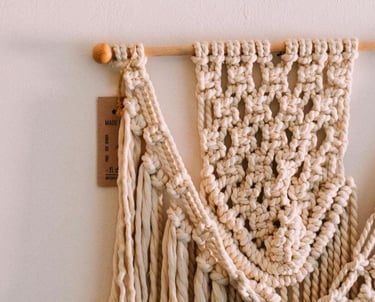 adorno con nudos elaborados con macramé y madera sobre pared blanca