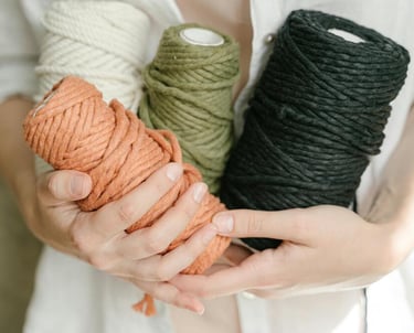 mujer sosteniendo hilos de macramé color blanco,verde,naranja y negro