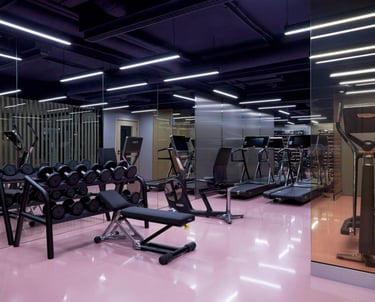 Bright fitness center with pink mat flooring, mirror walls, LED lighting, treadmills, dumbbell rack.
