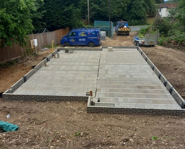 A beam and block floor installation on a new house construction site with work vans in the background.
